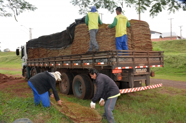 Funcionários descarregam grama que será plantada nos taludes no entorno da futura quadra de vôlei de areia