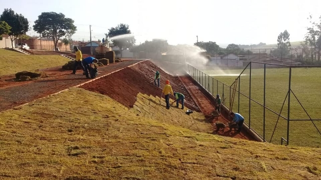 Plantio de grama esmeralda no entorno do campo de futebol society, no Jardim do Caju